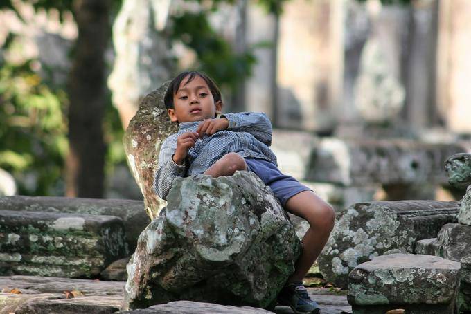 Criança sentada Bayon Angkor Thom, Angkor, Camboja