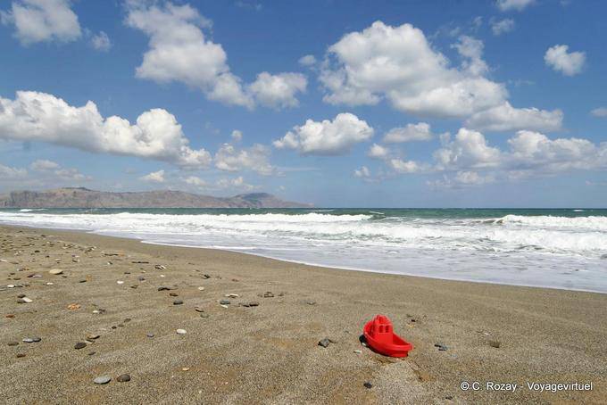 Barco de plástico e seixos na praia de areia, Georgioupoli - Creta, Grécia
