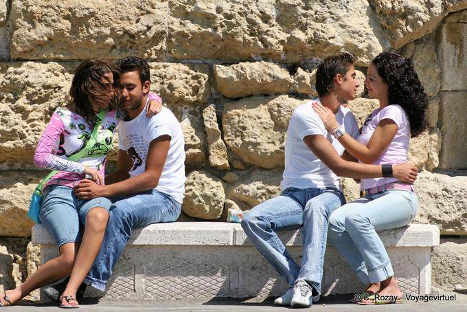 Amantes que smooch em bancos públicos, Heraklion - Creta, Grécia