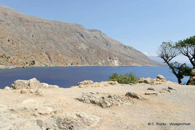 Terra, rocha descascado seco e mar no exterior Loutro - Creta, Grécia