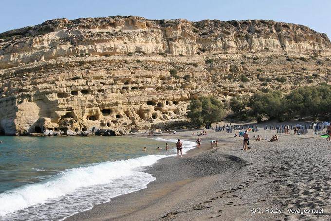 A praia em arco e do local protegido das cavernas túmulo de Matala - Creta, Grécia