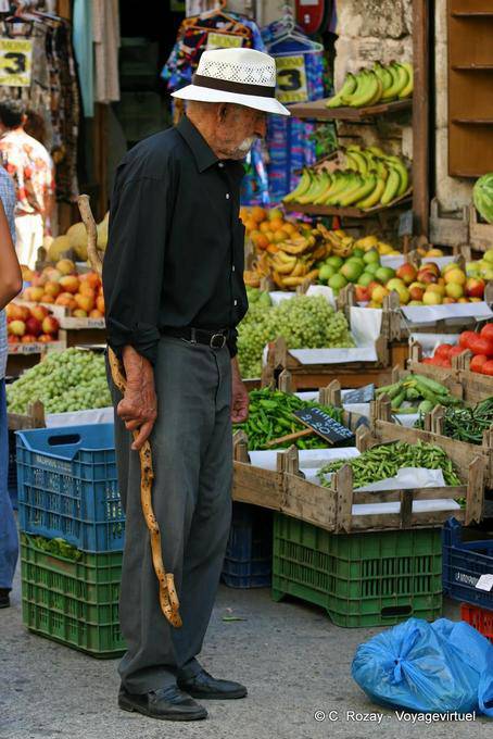 Cana-de-cretense em frente a uma barraca de frutas e vegetais, Rethymnon - Creta, Grécia