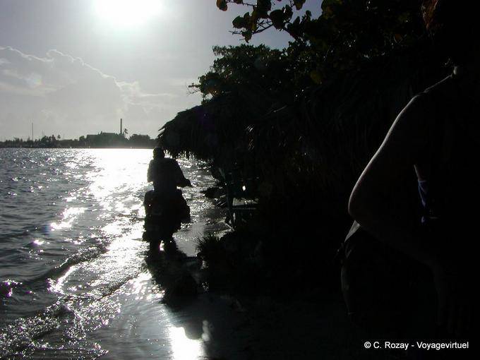 Contra a luz, motocicleta passando sobre as ondas, Boca Chica, Rep. Dominicana