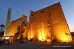 O pilão de Ramsés II, e staues obelisco colossal iluminação visão noturna, Luxor, Egipto.