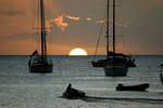 Deshaies, definindo metade sol entre barcos na silhueta, Guadalupe.