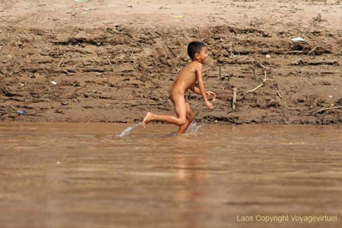 Jovem Lao correr nu na margem do Mekong Laos Sud, Laos