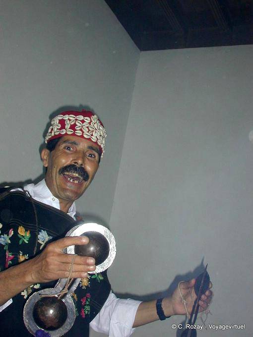 Luz alucinatória de Gnawa músico segurando um qarqabus, Essaouira - Marrocos