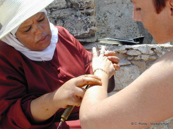 Um artista de tatuagem de henna oficiando perto das muralhas, Essaouira - Marrocos