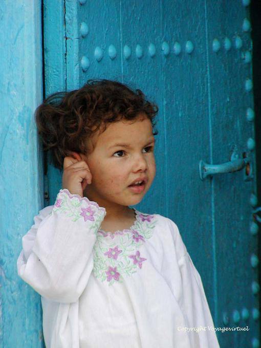 Uma criança em uma porta, Chefchaouen - Marrocos