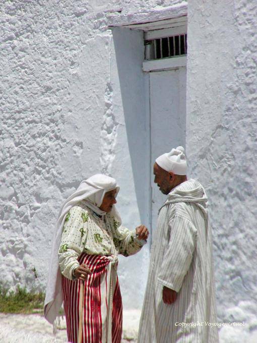 Mulher que desgasta mendile avental saia e homem djellaba, Chefchaouen - Marrocos