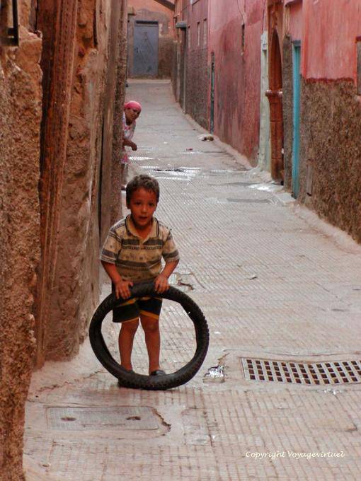 Uma criança que joga com uma pista de pneu da Medina, Marrakech - Marrocos