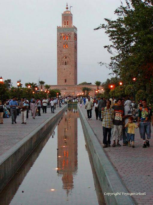 Reflexão do minarete iluminado em um lago no jardim da Koutoubia, Marrakech - Marrocos