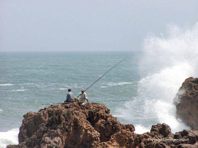 Espuma e pescadores sobre as rochas do passe, Oualidia - Marrocos