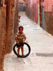Uma criança que joga com uma pista de pneu da Medina, Marrakech, Marrocos.