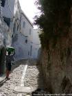 Calçamento de ruas de paralelepípedos e criança que veste a roupa na cabeça, Chefchaouen, Marrocos.
