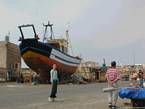O barco de pesca de madeira em doca seca no banco dos réus, Essaouira, Marrocos.