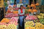 Vendedora entre maçãs e laranjas no mercado, Nuwara Eliya, Ceilão Sri Lanca.